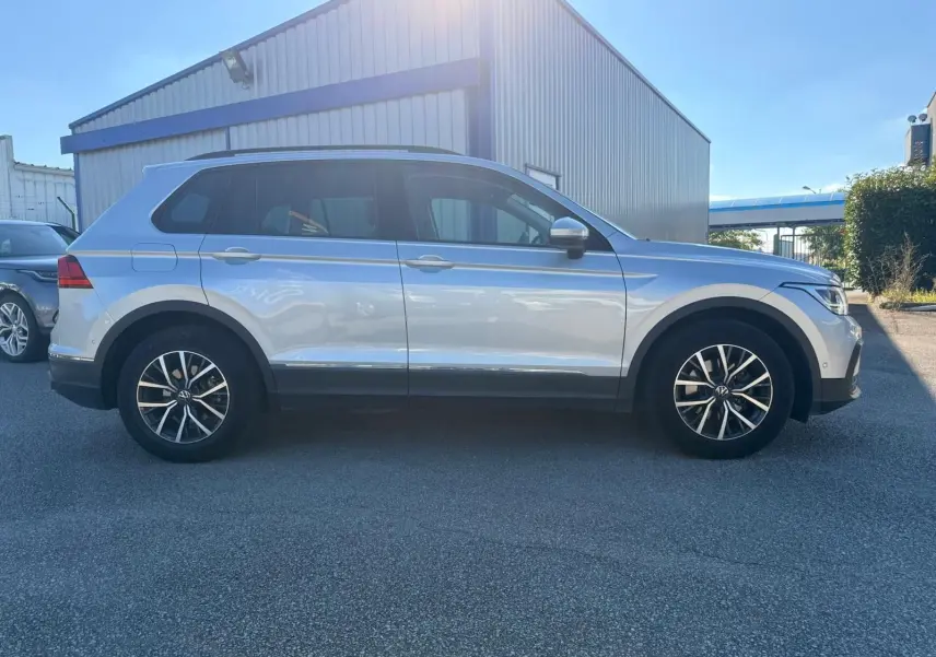 Volkswagen Tiguan 1.5 TSI 150CH LIFE DSG7 en reflet argent vu de profil côté gauche, avec jantes alliage et vitres teintées.