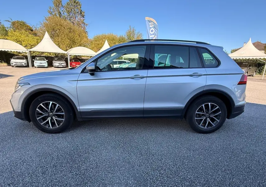 Profil côté gauche d'un Volkswagen Tiguan 1.5 TSI 150CH LIFE DSG7 en reflet argent avec jantes alliage noires.