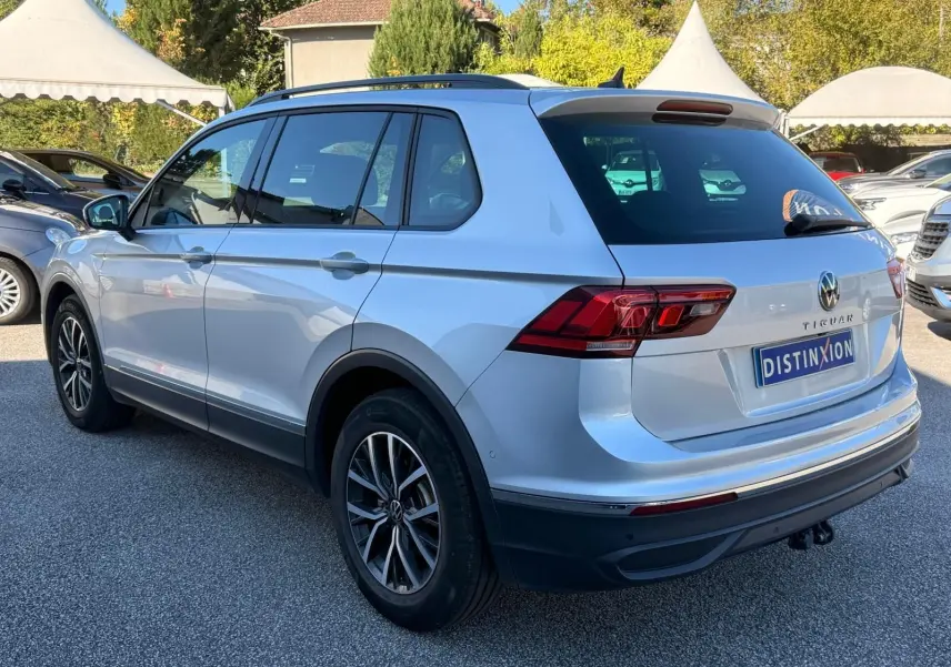 Volkswagen Tiguan reflet argent vu de trois quarts arrière droit, avec jantes alliage et hayon fermé sur parking.