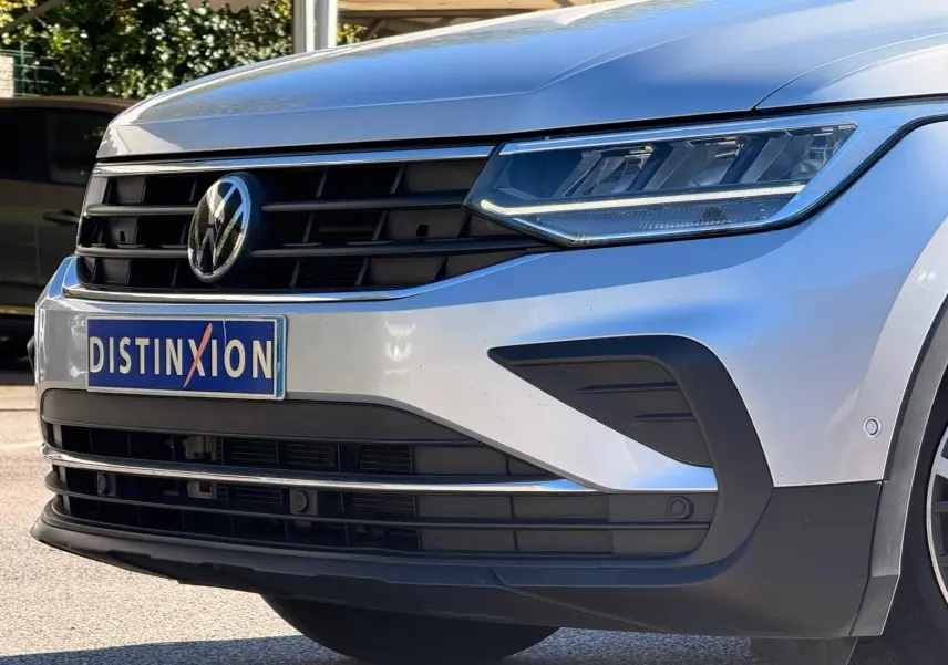 Gros plan sur l'avant droit d'un Volkswagen Tiguan 2021 reflet argent avec calandre noire et phares LED distinctifs.
