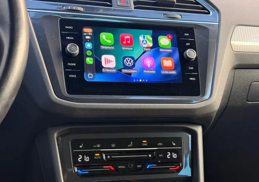 Tableau de bord du Volkswagen Tiguan 1.5 TSI 150CH Life 2021, écran tactile et commandes climatisation visibles.