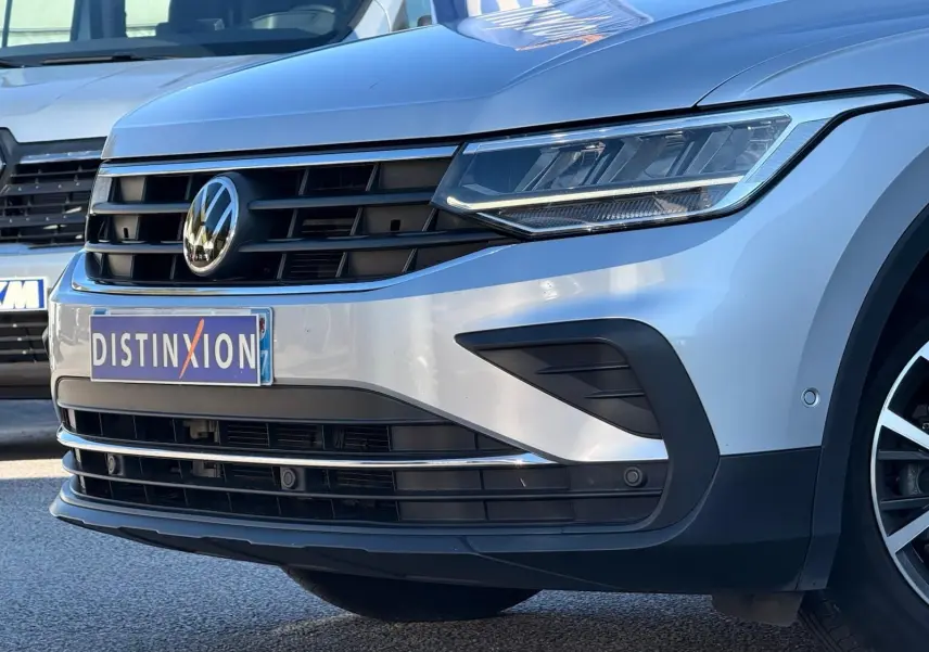 Vue 3/4 avant droit d'un Volkswagen Tiguan 2021 en reflet argent, mettant en valeur sa calandre noire et ses phares LED.