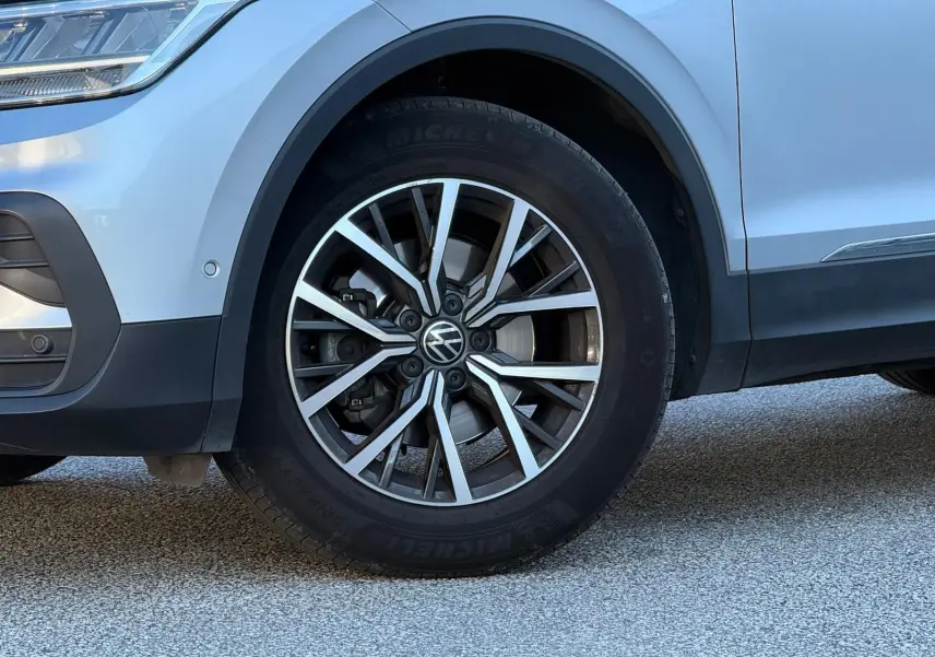Gros plan sur la roue avant gauche d'un Volkswagen Tiguan 2021 reflet argent, avec jante alliage et logo VW visible.