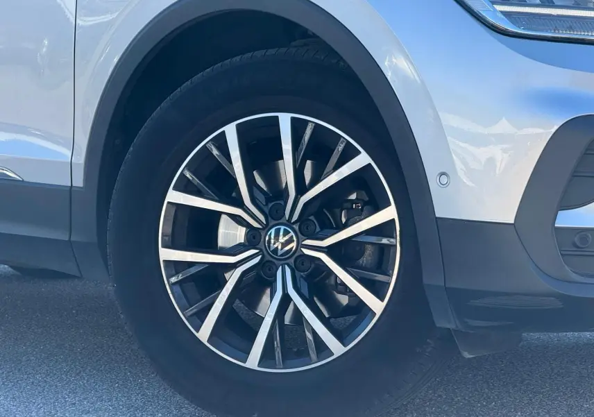 Gros plan sur la roue avant gauche du Volkswagen Tiguan 2021 en reflet argent avec jante alliage noire et argentée.
