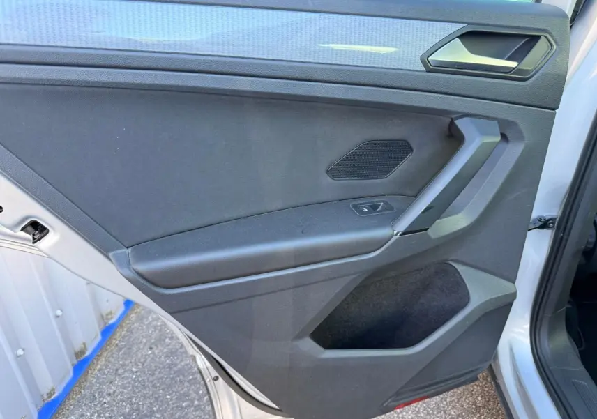 Porte arrière droite ouverte du Volkswagen Tiguan 1.5 TSI 150CH Life 2021 en reflet argent, intérieur noir avec poignée angulaire.