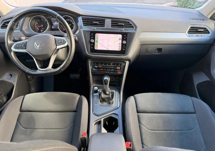 Vue intérieure avant du Volkswagen Tiguan 1.5 TSI 150CH LIFE DSG7 avec tableau de bord noir et écran tactile central affichant une carte.