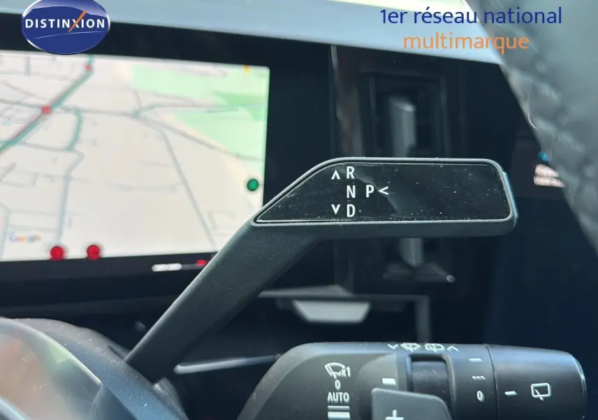 Le levier de vitesses automatique du Renault Austral 2023 en gros plan avec l'écran de navigation en arrière-plan.