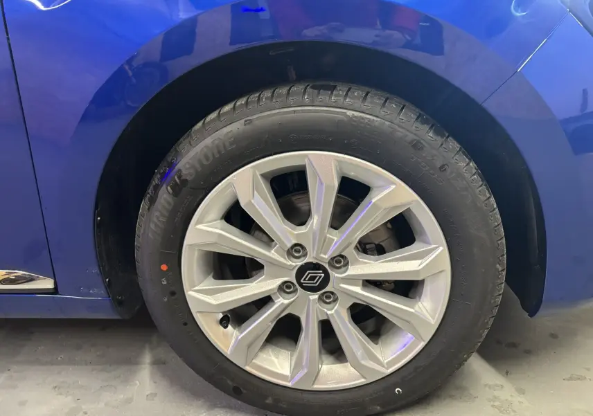 Gros plan sur la roue avant gauche de la Renault Clio TCE 90CH X-TRONIC Evolution 2024 en bleu Iron, jante argentée.