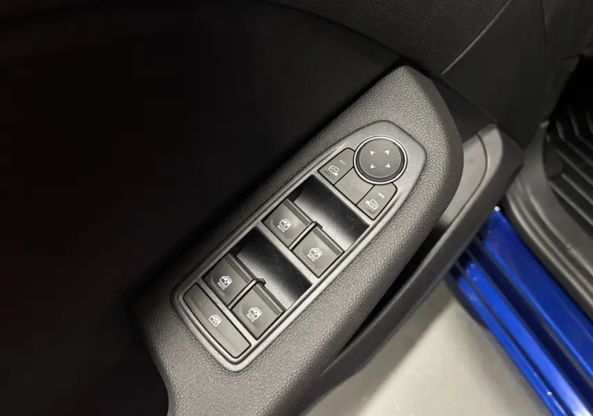 Gros plan sur les commandes des vitres électriques côté conducteur d'une Renault Clio 2024 bleu iron, intérieur noir.