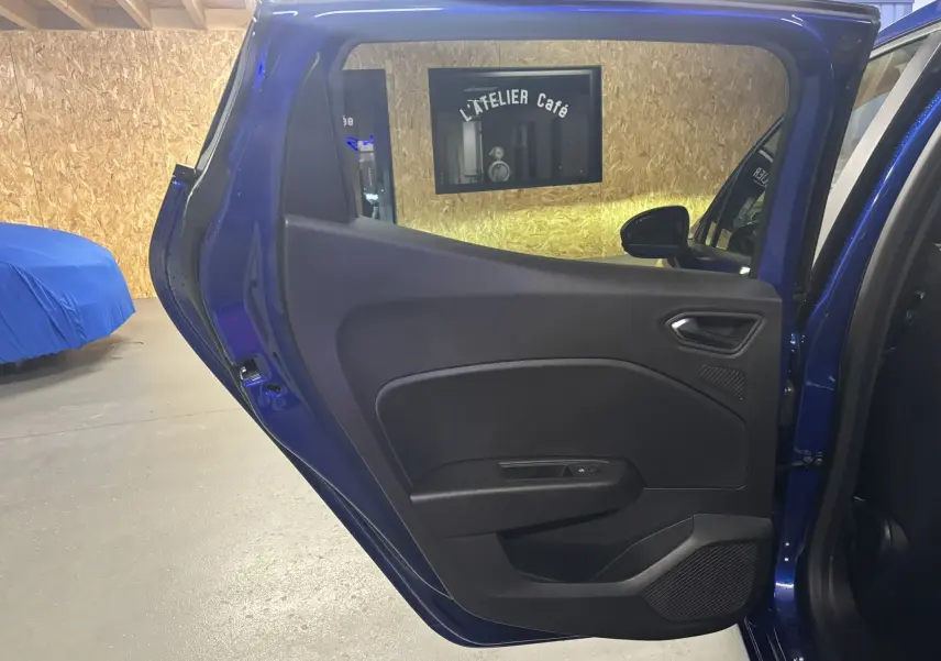 Vue intérieure de la porte arrière gauche bleu iron d'une Renault Clio 2024 avec garniture noire et poignée argentée.