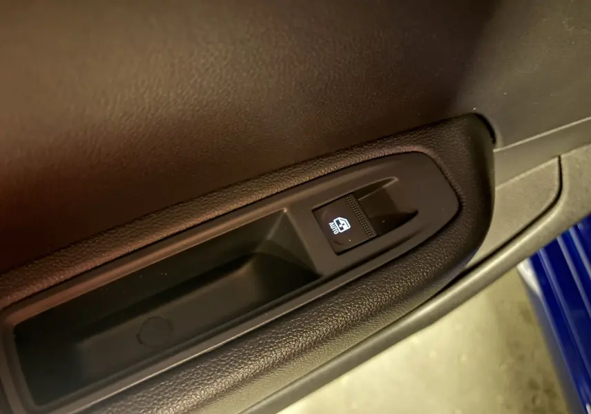 Bouton de commande de lève-vitre éclairé sur la porte intérieure côté gauche d'une Renault Clio Bleu Iron 2024.