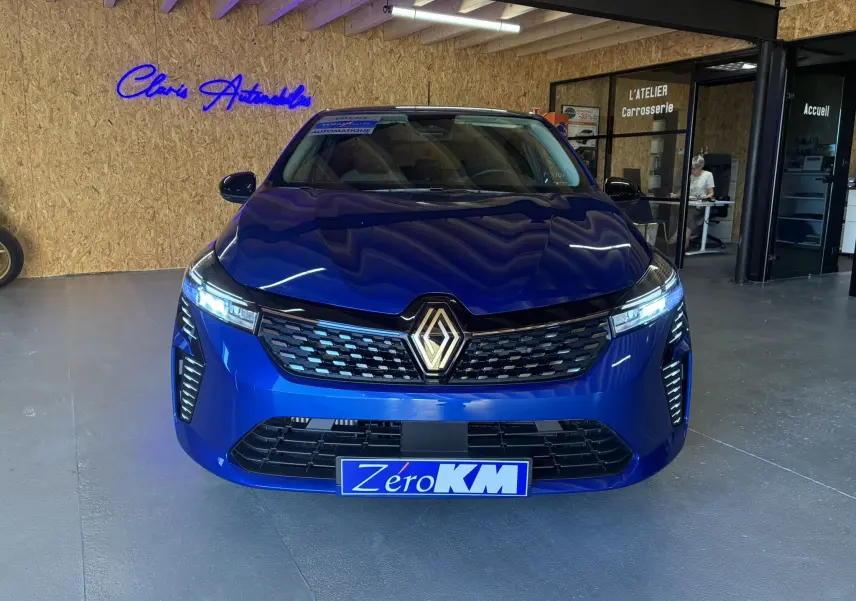 Vue frontale d'une Renault Clio TCE 90CH X-TRONIC Evolution bleu iron avec calandre noire et phares LED allumés.