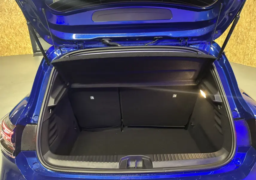 Coffre ouvert de la Renault Clio TCE 90CH X-TRONIC Evolution 2024 en bleu iron, vue arrière montrant l'espace de rangement vide.