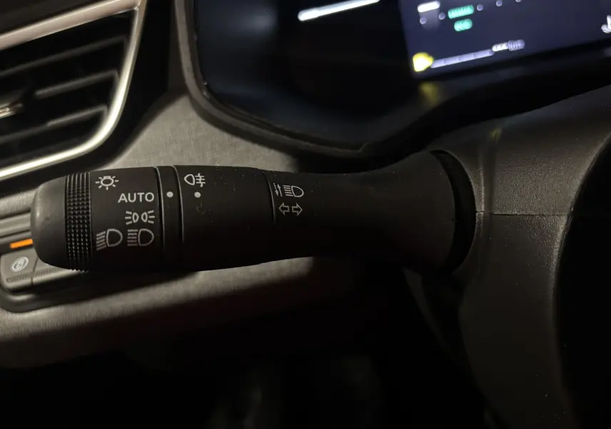 Gros plan sur la manette de commande des feux et clignotants à gauche du volant d'une Renault Clio bleu Iron 2024.