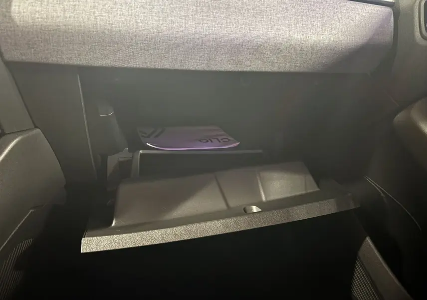 Gros plan sur la boîte à gants ouverte de la Renault Clio 2024, tissu gris noir visible sur la planche de bord.