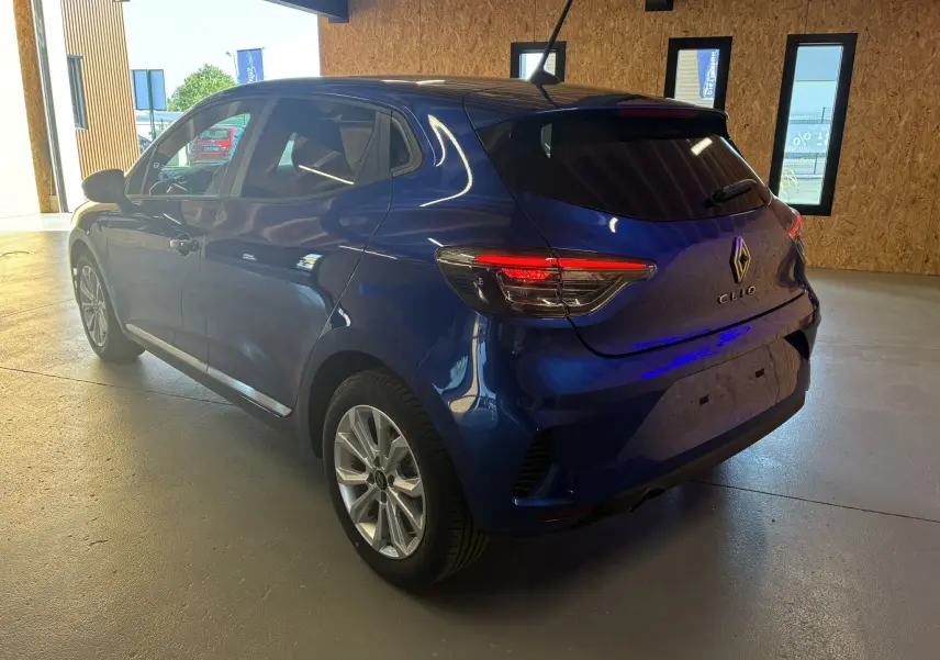 Renault Clio TCe 90ch Evolution bleu Iron vue 3/4 arrière droit en intérieur avec feux arrière allumés.