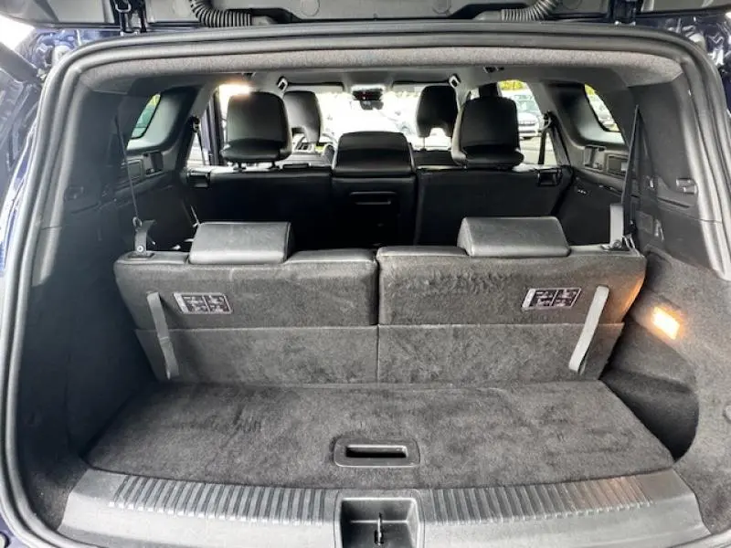 Coffre ouvert vu de l'arrière du Renault Espace Bleu Nocturne 2023, montrant la troisième rangée de sièges noirs relevés.