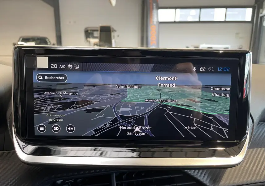 Écran tactile du système de navigation Peugeot 208 2025 affichant une carte en mode 3D, intérieur noir.
