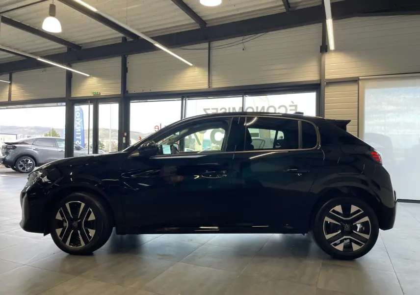 Profil côté gauche d'une Peugeot 208 noire 2025 avec jantes alliage bi-ton et vitres teintées en showroom.