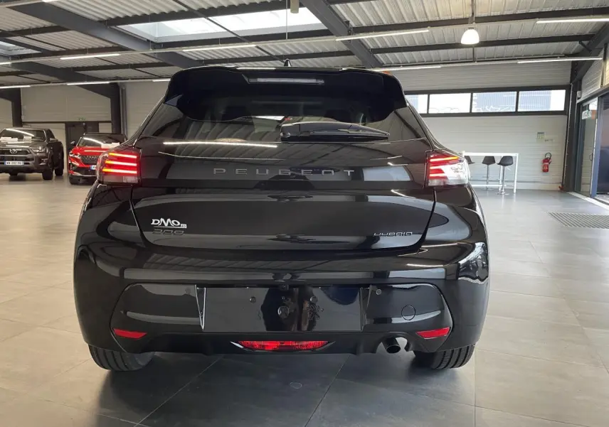 Vue arrière d'une Peugeot 208 noire avec feux arrière à LED en forme de griffes dans un showroom.