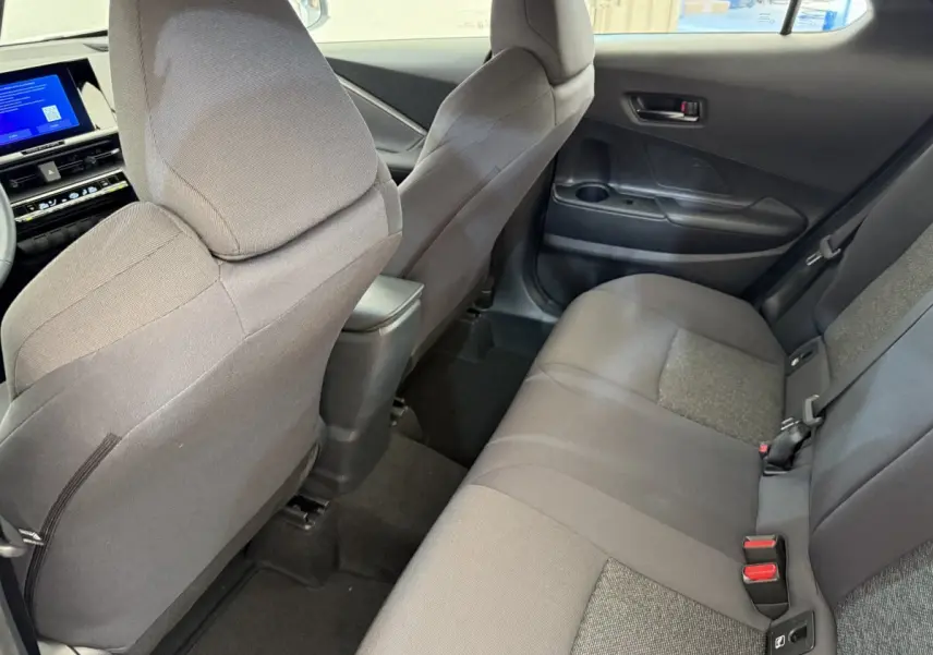 Vue intérieure arrière côté droit du Toyota C-HR 1.8 Hybride 140 Dynamic, sièges tissu gris et console centrale noire.