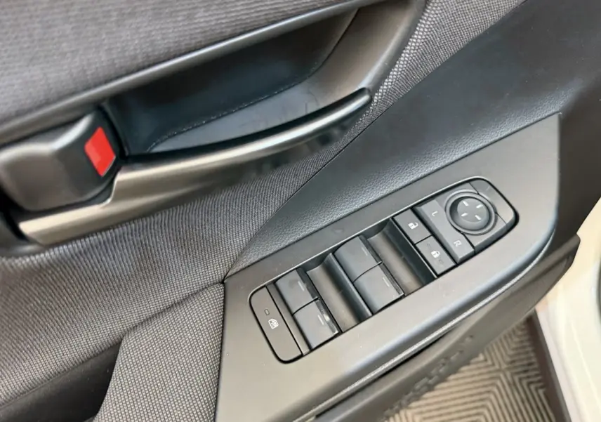 Vue rapprochée de la porte avant gauche blanche du Toyota C-HR 2024, avec commandes électriques et poignée noire.