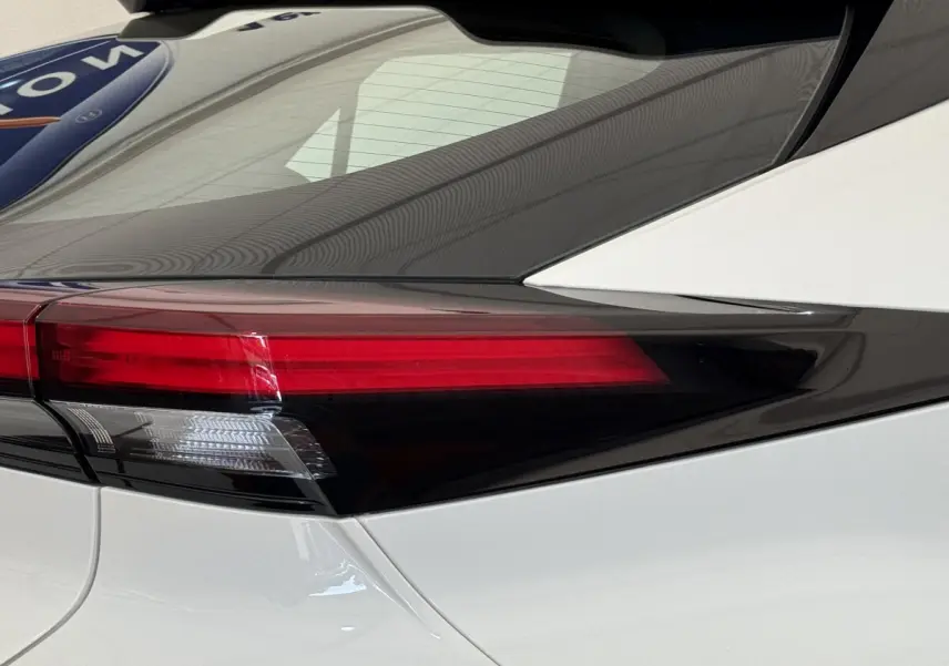 Gros plan sur le feu arrière droit du Toyota C-HR 1.8 Hybride blanc, soulignant ses lignes anguleuses et son vitrage teinté.