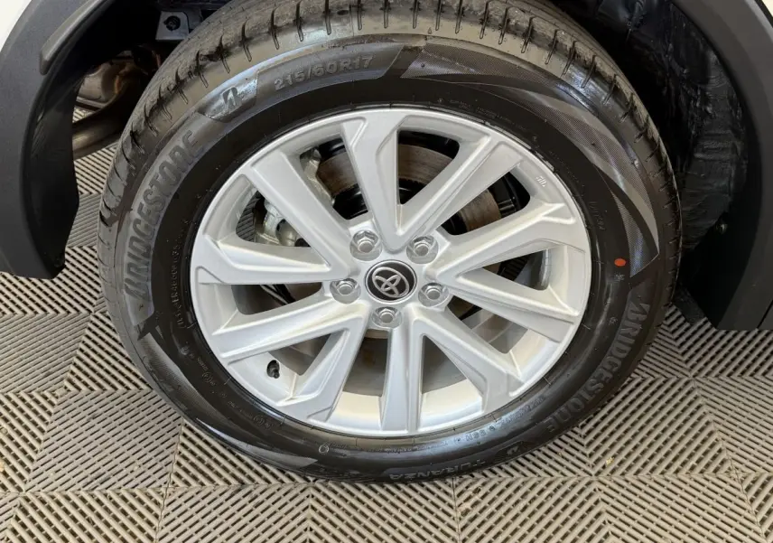 Gros plan sur la roue avant droite du Toyota C-HR 1.8 Hybride blanc avec jante alliage argentée et pneu Bridgestone.