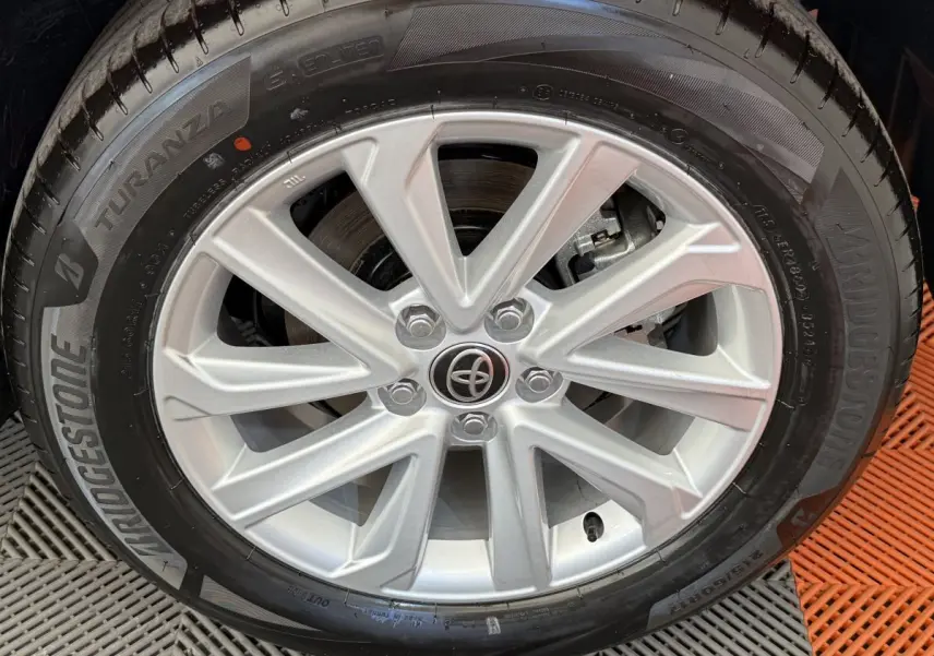 Gros plan sur la jante alliage argentée avec logo Toyota au centre, montée sur un pneu Bridgestone noir.