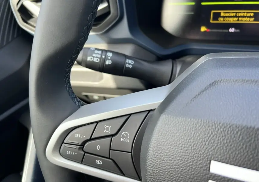 Gros plan sur le volant cuir noir côté gauche du Dacia Bigster 2026 avec commandes intégrées et affichage digital partiel.