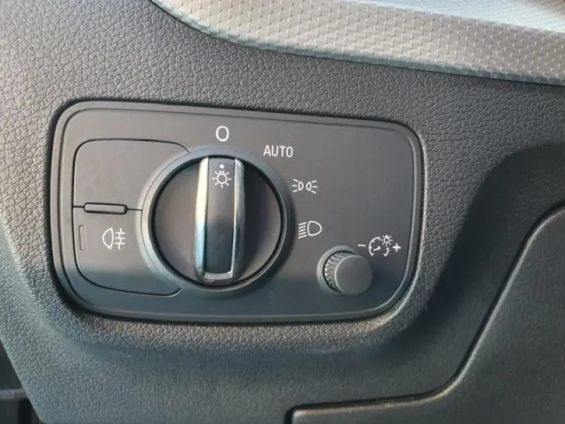 Gros plan sur la commande d’éclairage intérieur de l’Audi Q2 30 TDI 116ch Design, finition noire texturée.