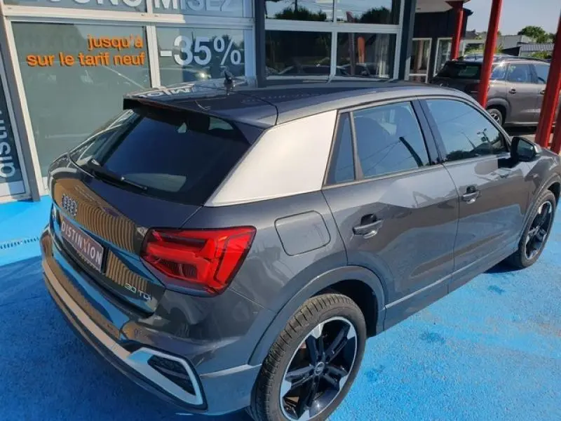 Audi Q2 30 TDI gris Manhattan métallisé vue 3/4 arrière droit avec toit noir et jantes noires.