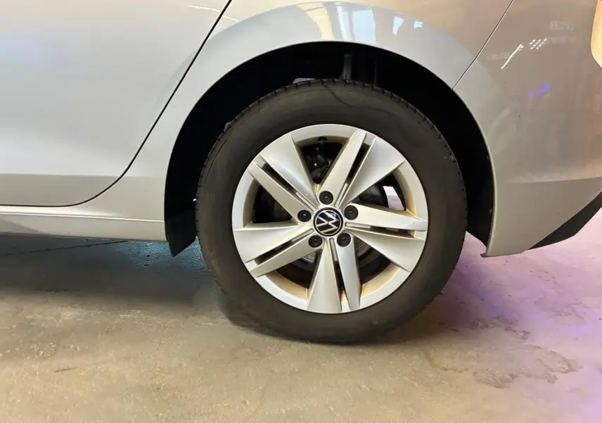 Gros plan sur la roue arrière droite d'une Volkswagen Golf gris clair 2023, jante alliage à cinq branches doubles.