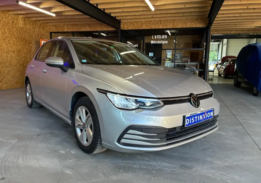 Volkswagen Golf 1.0 eTSI gris clair vue 3/4 avant droit dans un garage avec éclairage intérieur.