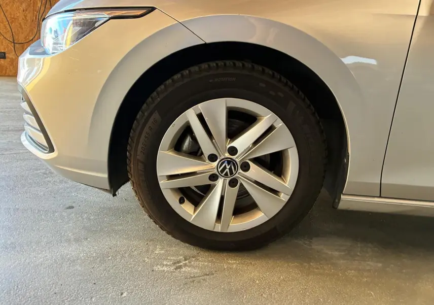 Gros plan sur la roue avant gauche d’une Volkswagen Golf gris clair 2023, avec jante alliage à cinq branches.
