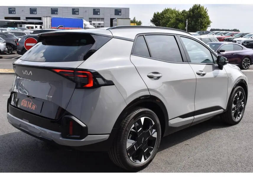 Vue 3/4 arrière droite du KIA Sportage hybride gris avec jantes noires et feux arrière LED distinctifs.