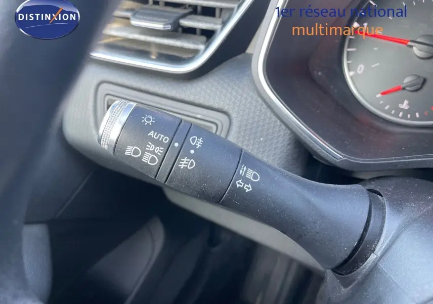 Gros plan sur la commande des feux et clignotants de la Renault Clio Société blanche, tableau de bord partiellement visible.