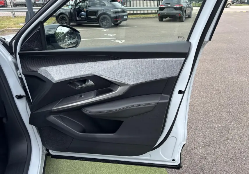 Porte avant gauche ouverte d'un Peugeot 3008 blanc Okenite, montrant le décor tissu gris et noir avec surpiqûres blanches.