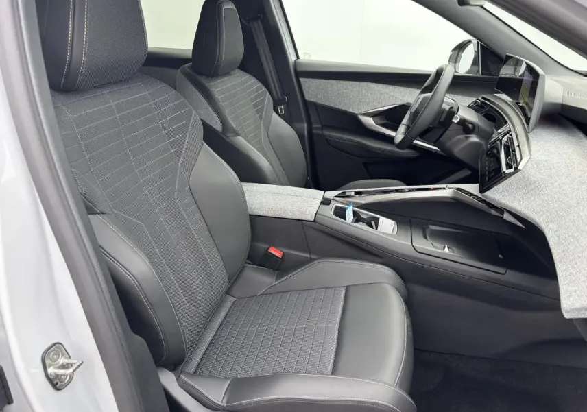 Intérieur avant droit du Peugeot 3008 blanc Okenite 2024 avec sièges tissu noir et tableau de bord gris chiné.