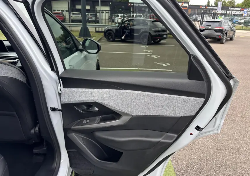 Vue intérieure de la porte arrière gauche blanche du Peugeot 3008 III 1.2 HYBRID 136 Allure avec décor tissu gris et noir.
