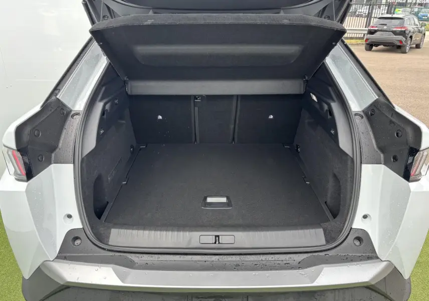 Coffre ouvert vu de l'arrière d'un Peugeot 3008 blanc Okenite 2024, avec intérieur noir et feux arrière LED visibles.