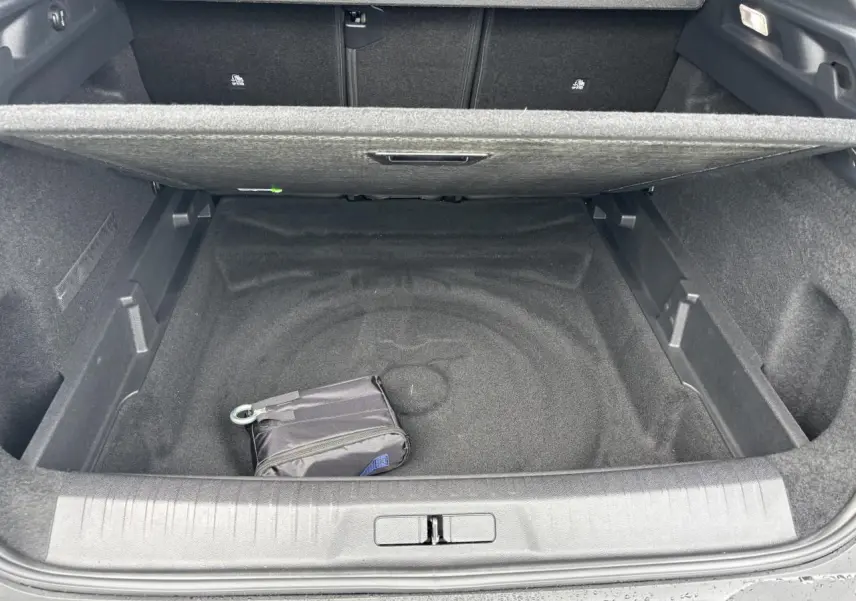 Coffre ouvert du Peugeot 3008 blanc Okenite 2024, montrant un espace de rangement vide avec un petit sac noir.