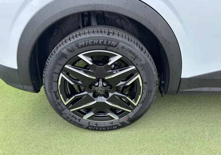 Gros plan sur la roue avant droite du Peugeot 3008 blanc Okenite avec jante alliage noire et diamantée 19 pouces.