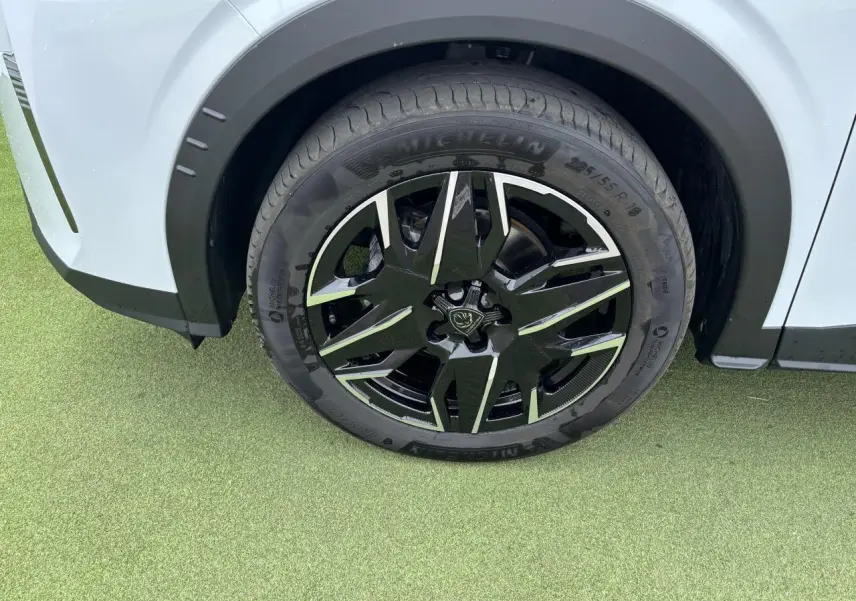 Gros plan sur la roue avant gauche noire et argentée du Peugeot 3008 blanc Okenite 2024.