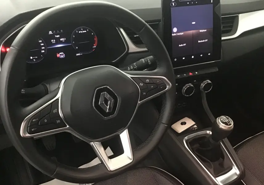 Vue intérieure du volant et console centrale du Renault Captur 2024, avec boîte manuelle et écran tactile vertical.