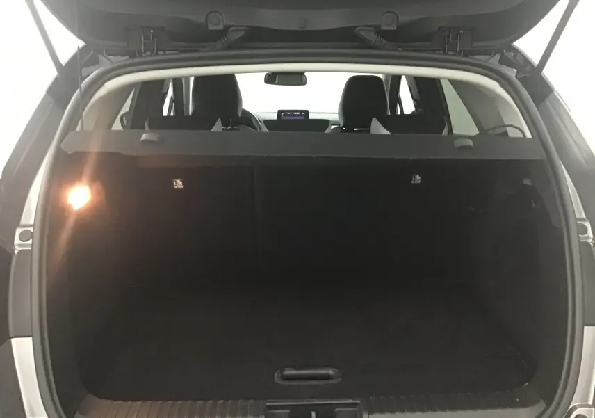 Coffre ouvert vu de l'arrière d'un Renault Captur gris cassiopée avec intérieur noir et tablette arrière visible.