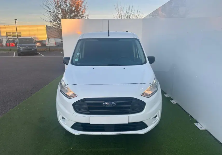 Vue frontale d'un fourgon Ford Transit Connect blanc avec calandre noire et phares allumés.