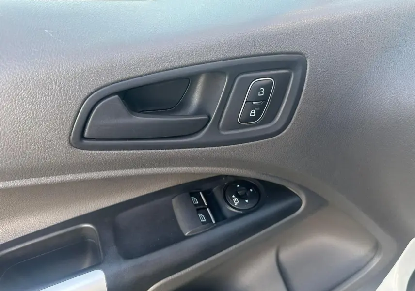 Gros plan sur la porte côté conducteur du Ford Transit Connect blanc, montrant les commandes de vitres et verrouillage.