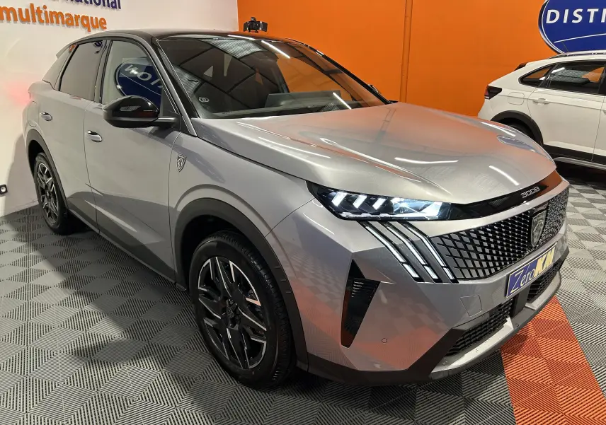 Vue 3/4 avant droite du Peugeot 3008 gris Artense avec phares LED allumés et calandre distinctive en intérieur showroom.
