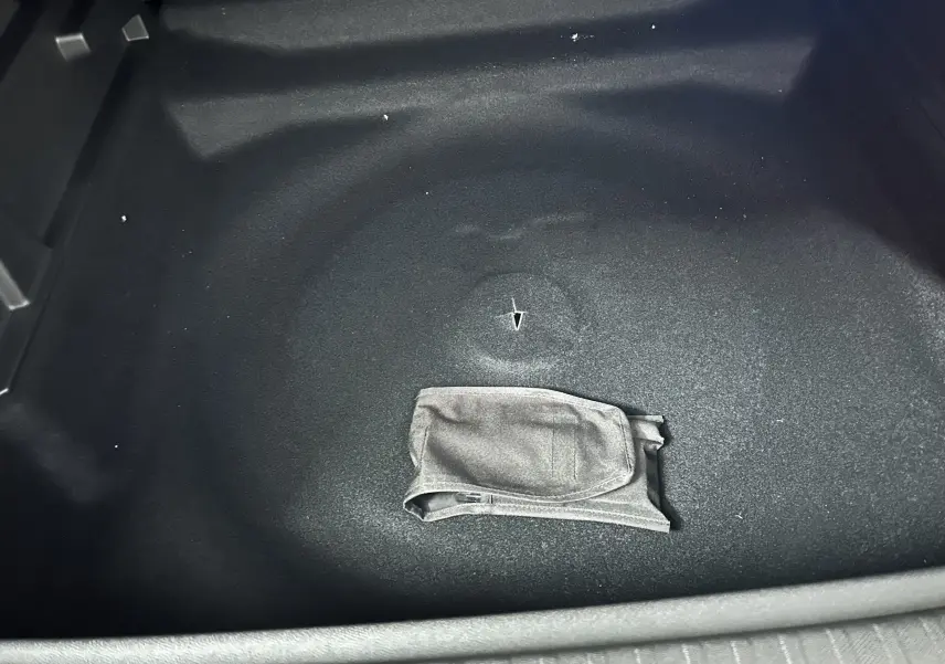 Vue rapprochée du coffre vide d’un Peugeot 3008 gris Artense avec un sac gris posé au centre.